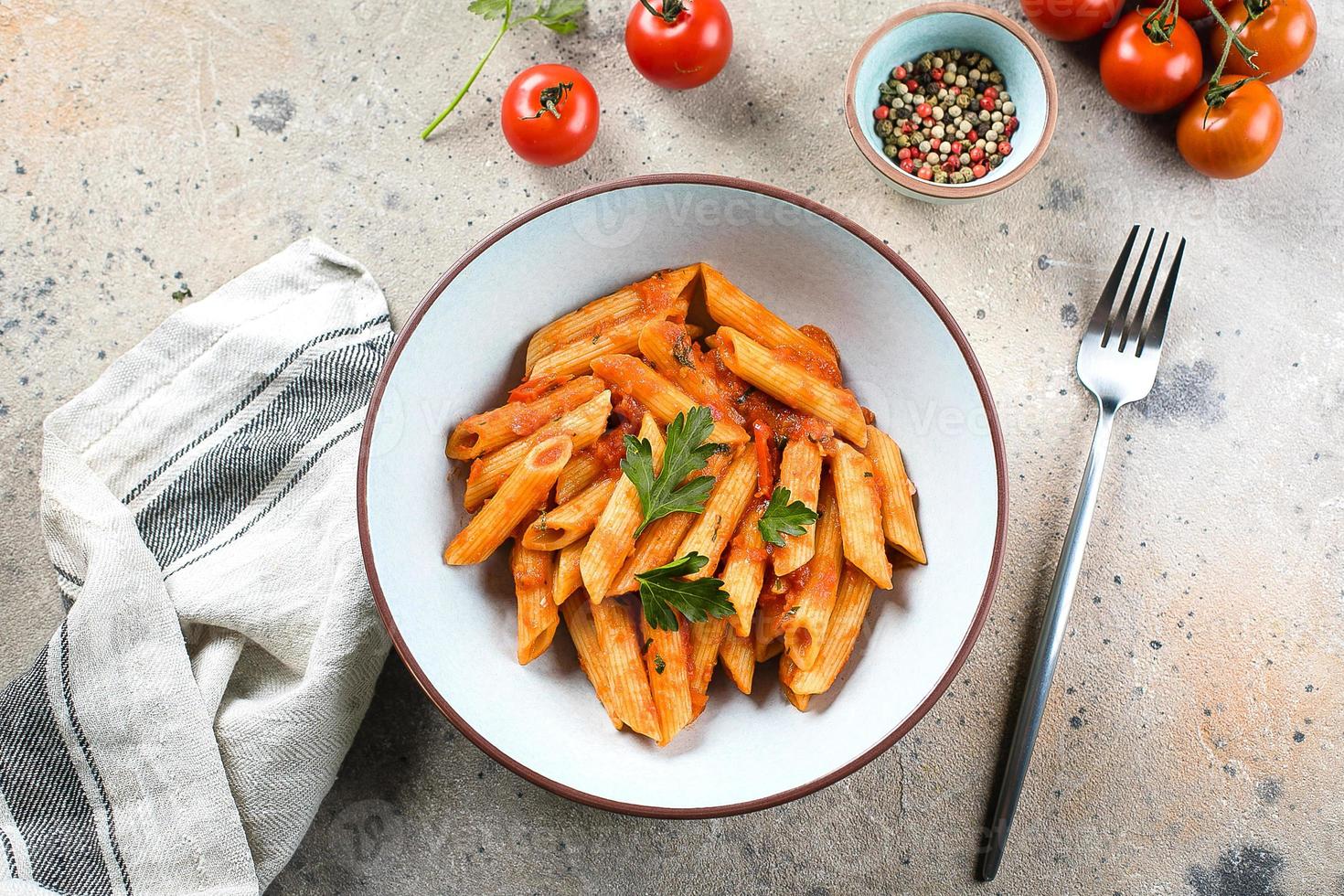 penne pasta met tomaat sausen in wit bord Aan steen achtergrond tafel. top visie. Italiaans voedsel foto