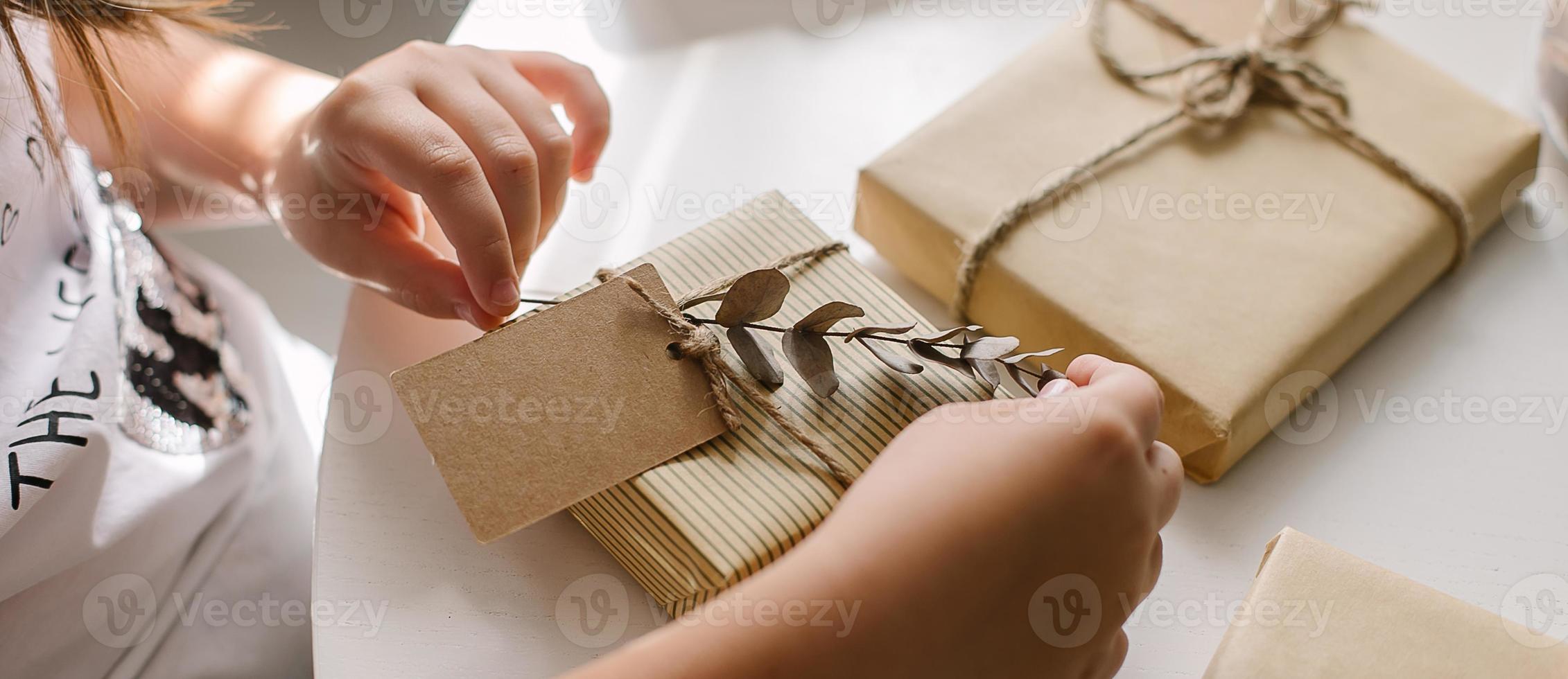 vrouw handen inpakken geschenk decor met eucalyptus en Notitie kar voor tekst. nul verspilling Kerstmis foto