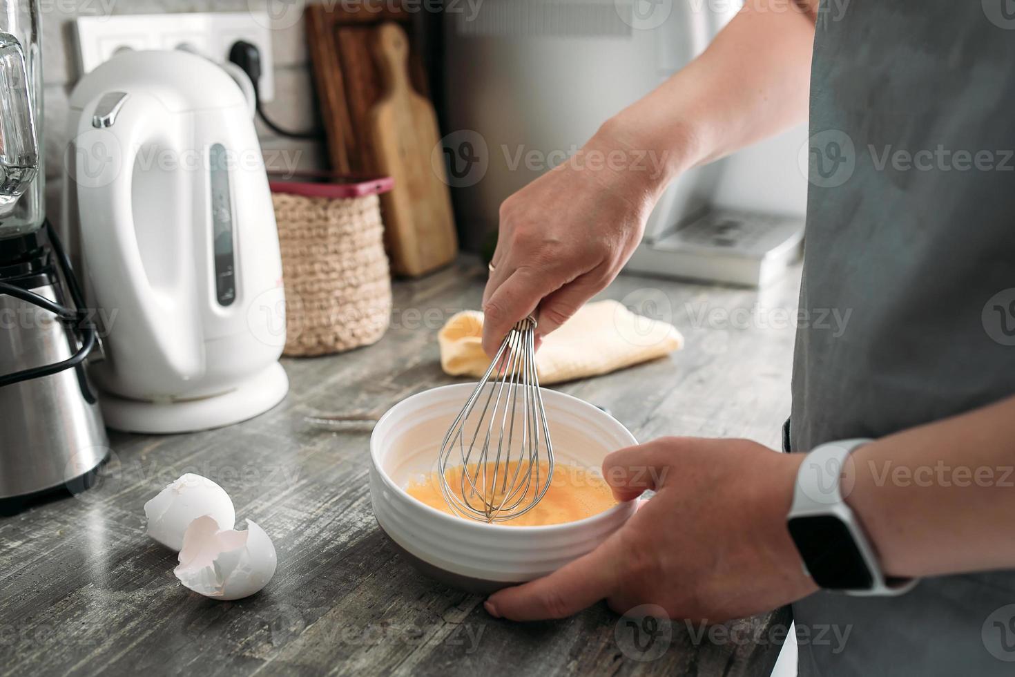 vrouw Koken ontbijt, beats eieren in de bord in de keuken. levensstijl, huis concept foto