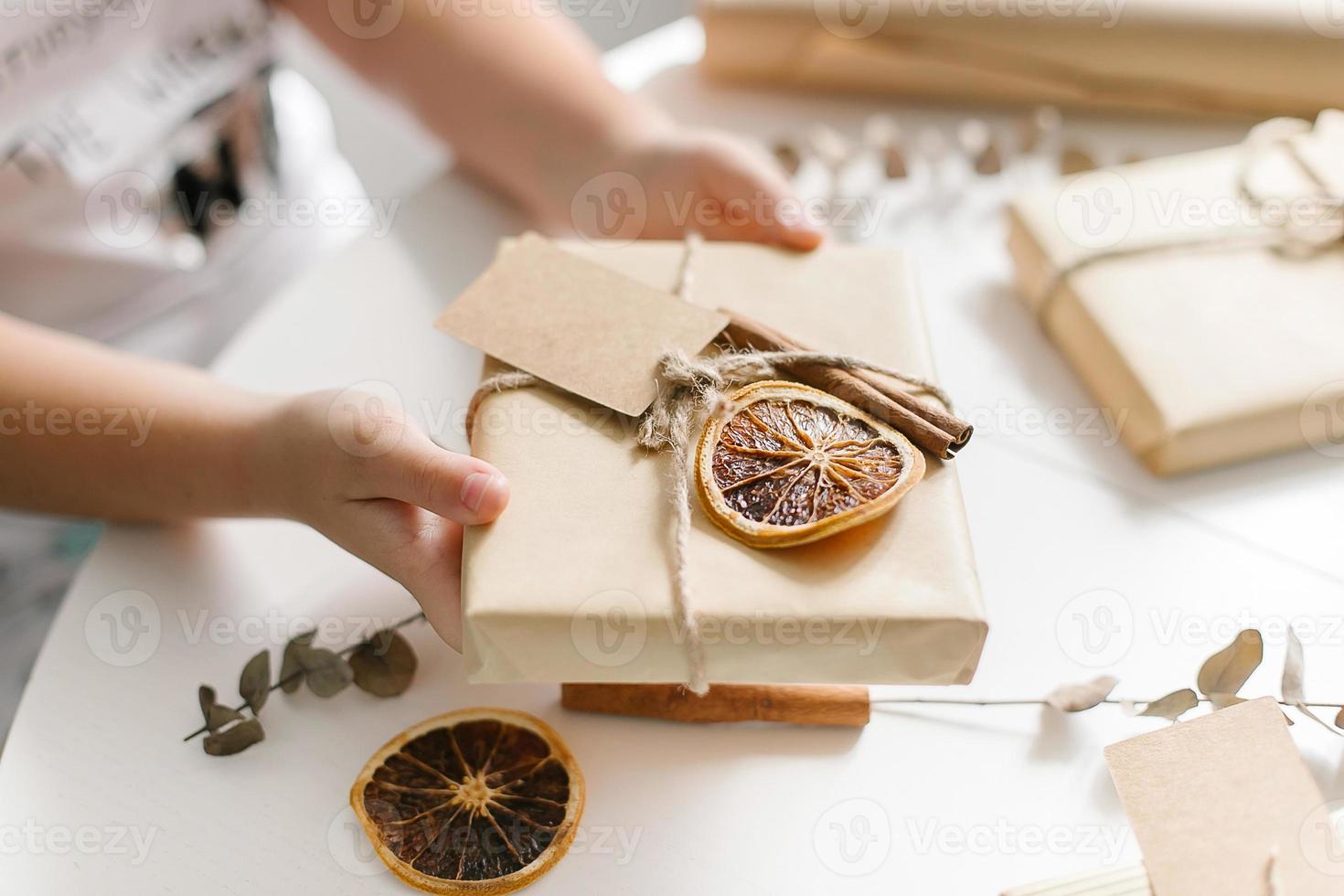 vrouw Holding een geschenk Cadeau omhulsel bruin ambacht papier en decoratie. concept van doe-het-zelf, eigengemaakt decor. foto