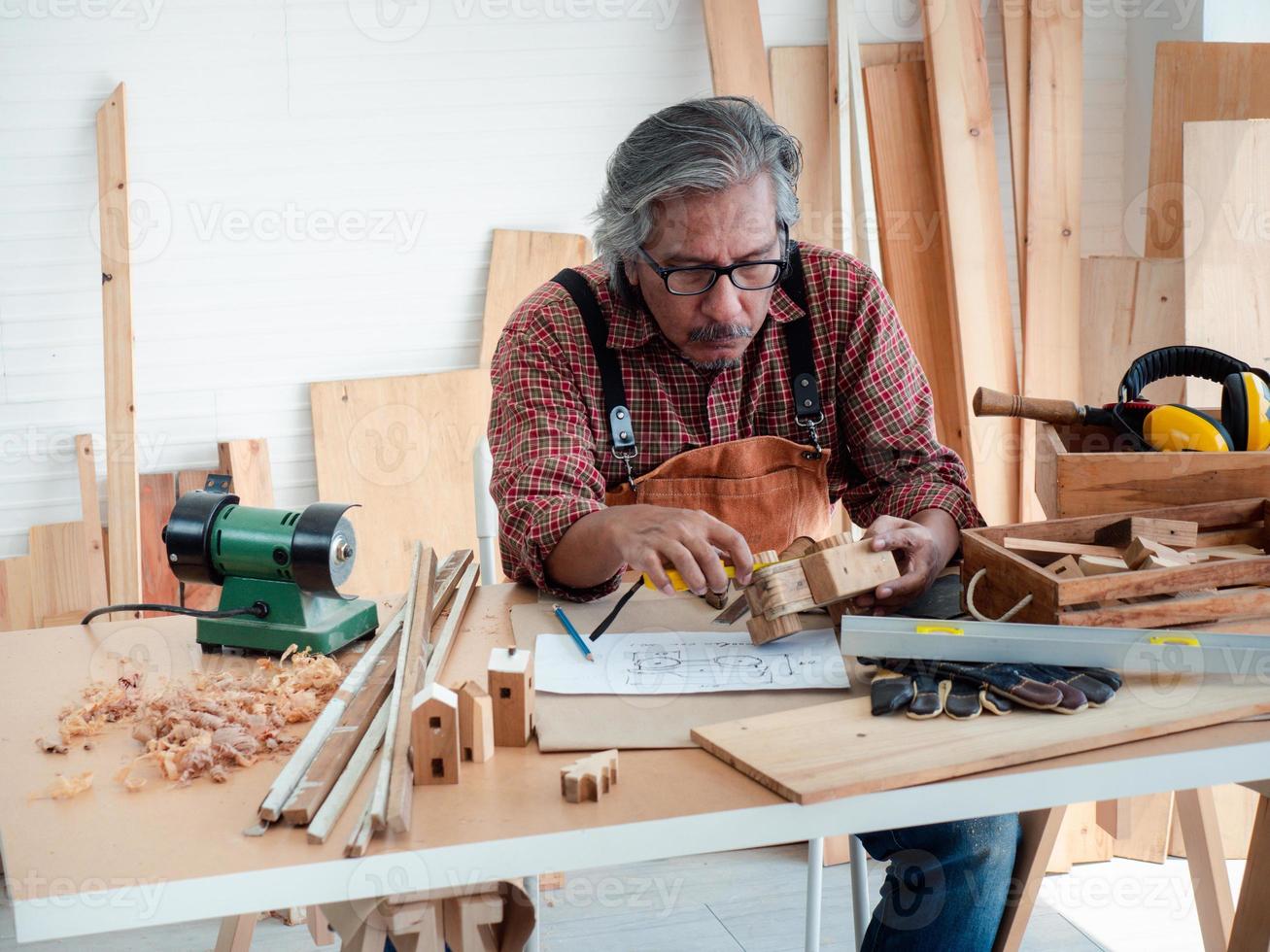 gelukkig Aziatisch senior Mens is genieten van zijn hobby door ijverig schilderij vogelhuisjes in de werkplaats. foto