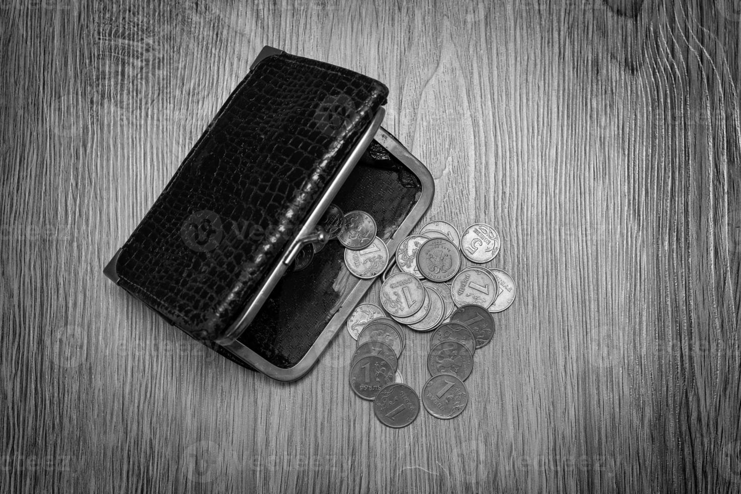 een oud versleten bruin portemonnee Aan een donker achtergrond met divers munten, inclusief een roebel. de concept van baan verlies, armoede foto