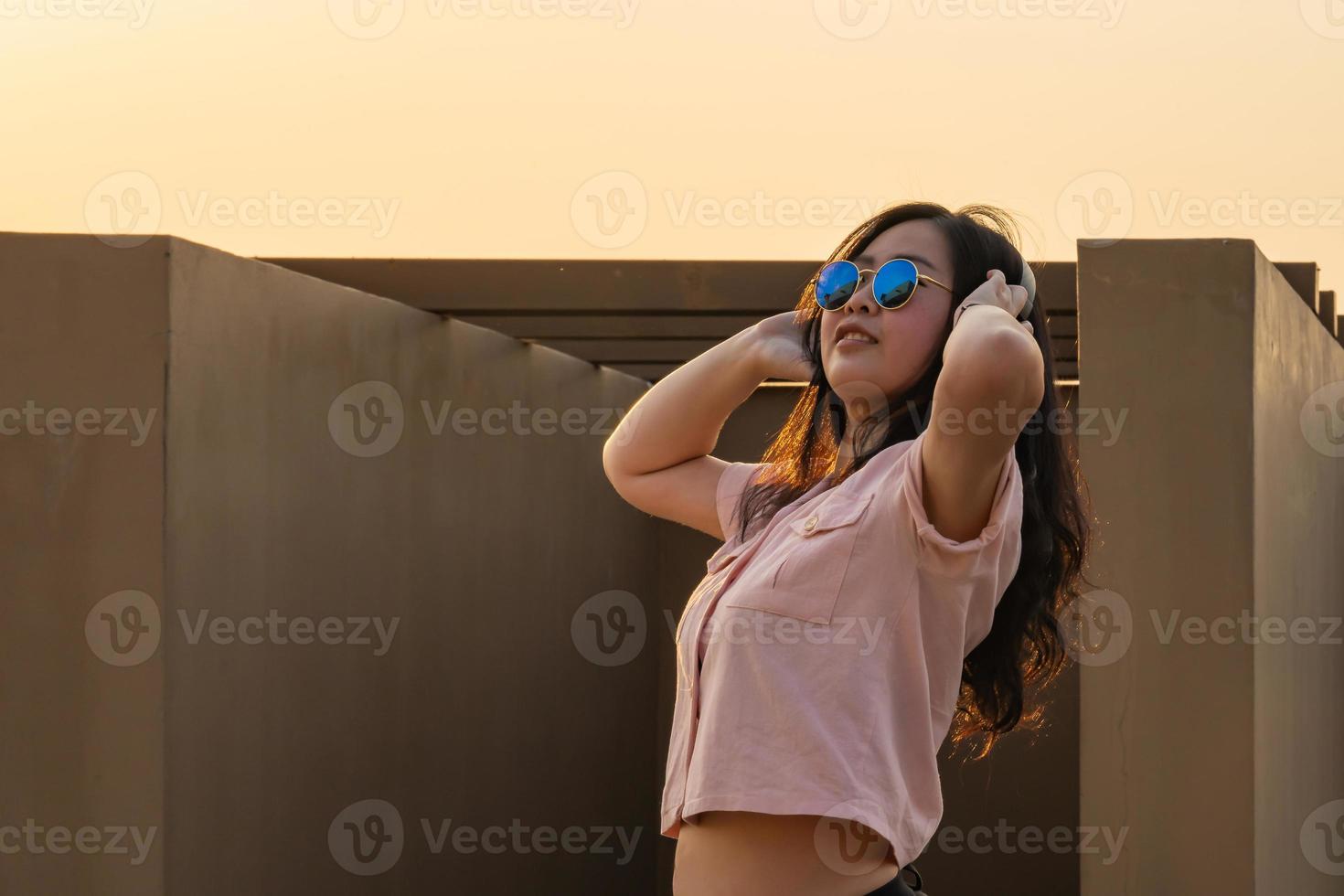 Aziatisch bril lang haar- meisje is dansen Aan de op het dak van de gebouw in schemering zonsondergang tijd. foto