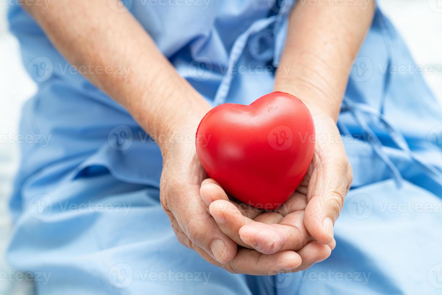 Aziatisch senior of ouderen oud dame vrouw geduldig Holding rood hart, gezond sterk medisch concept. foto