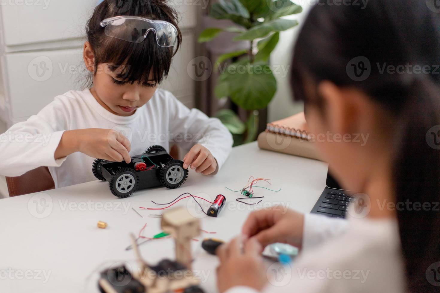 azië studenten leren thuis in het coderen van robotauto's en elektronische bordkabels in stam, stoom, wiskunde engineering wetenschap technologie computercode in robotica voor kinderen concept. foto