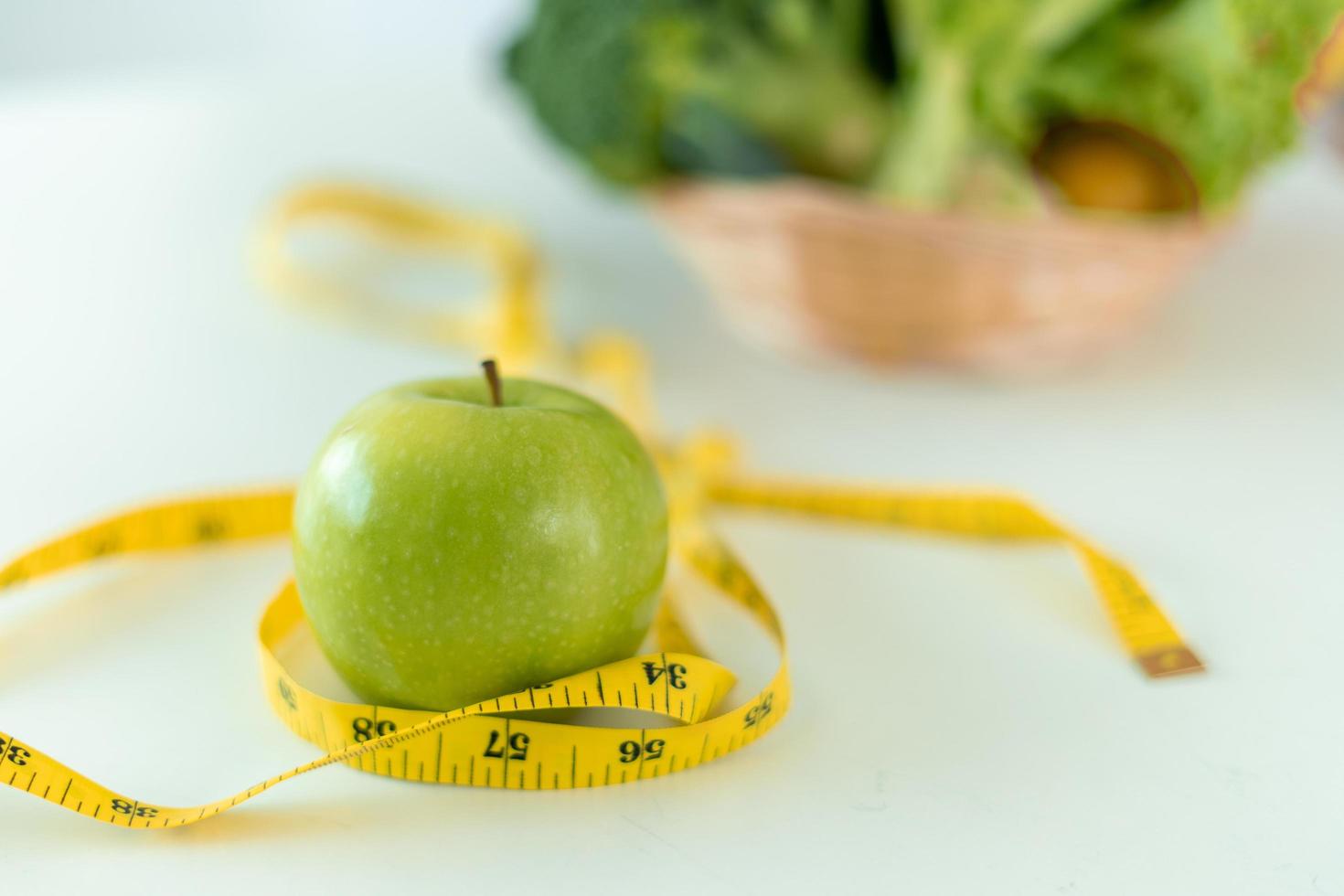 eetpatroon concept. groen appels en plakband meten met met een moedig salade Aan de tafel. aan het eten voedingsmiddelen met hoog vitamines voor Gezondheid en gewicht verlies. foto
