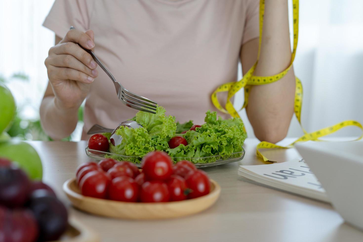gezond voedsel. Dames plan dieet voor slank vorm en gezond. vrouw aan het eten groenten, salade en tomaten foto