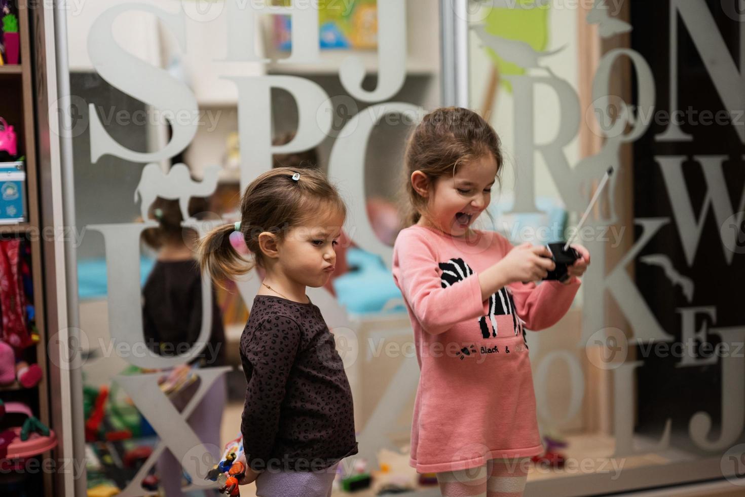 twee zussen Speel afgelegen controle in kinderen kamer. foto