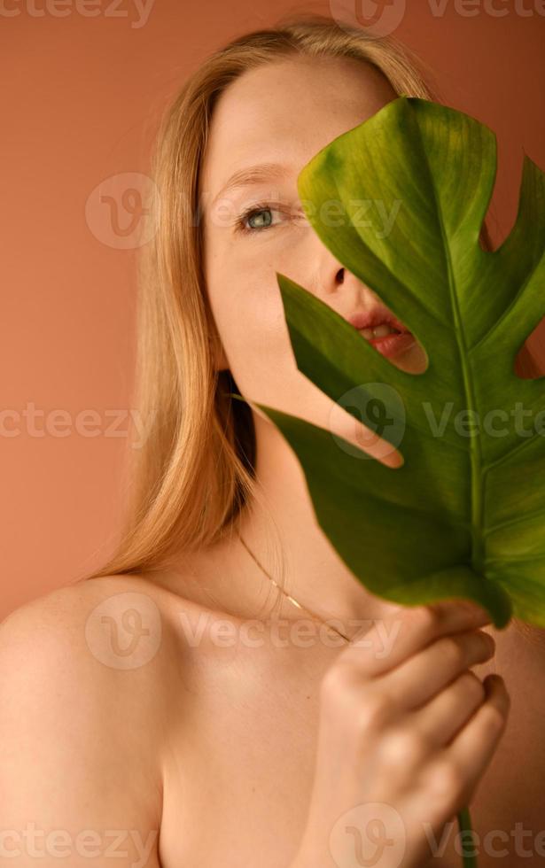 mooi vrouw met een glad huid Holding groen tropisch blad foto