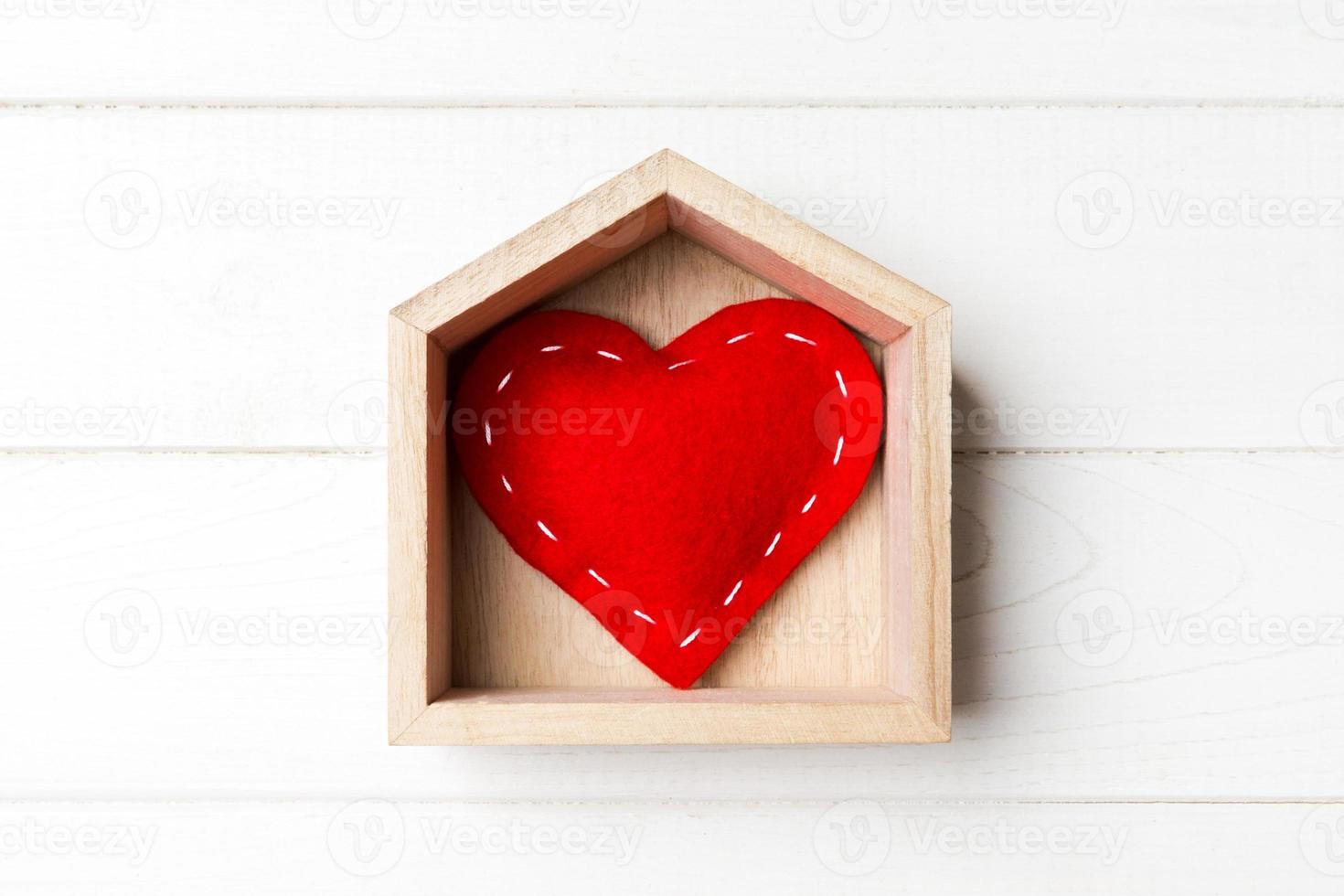 top visie van rood textiel hart in een huis Aan houten achtergrond. huis zoet huis concept. Valentijnsdag dag foto