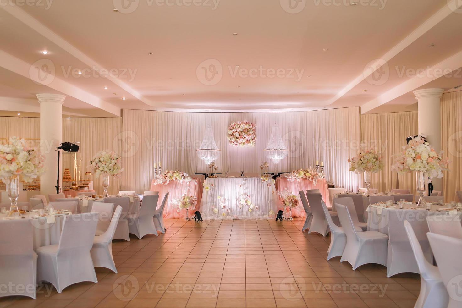 feestelijk bruiloft tafel decoratie met kristal kroonluchters, gouden kandelaars, kaarsen en wit roze bloemen . elegant bruiloft dag foto