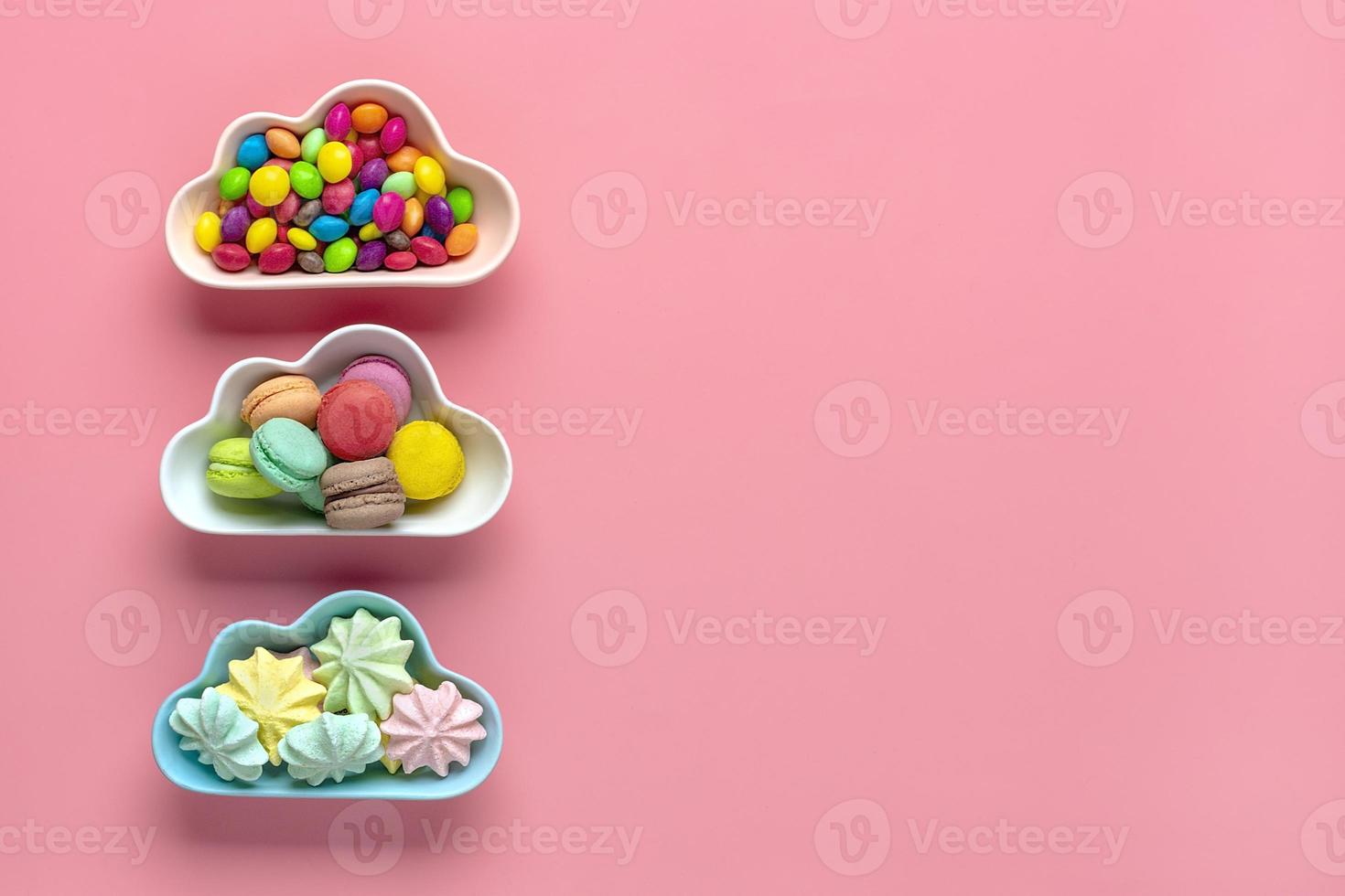 kleurrijk snoepjes - lolly, schuimgebakjes, bitterkoekjes in kom in vorm van wolk geïsoleerd Aan roze achtergrond vlak leggen top visie knolling ongezond en smakelijk voedsel creatief concept vakantie kaart foto