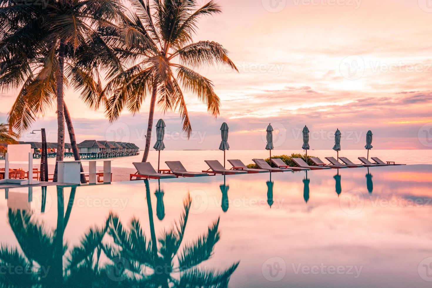 luxe zwemmen zwembad Aan de strand, rustig tafereel van exotisch tropisch landschap met kopiëren ruimte, zomer achtergrond voor vakantie vakantie. mooi zwembad en zonsondergang lucht. luxueus tropisch strand foto