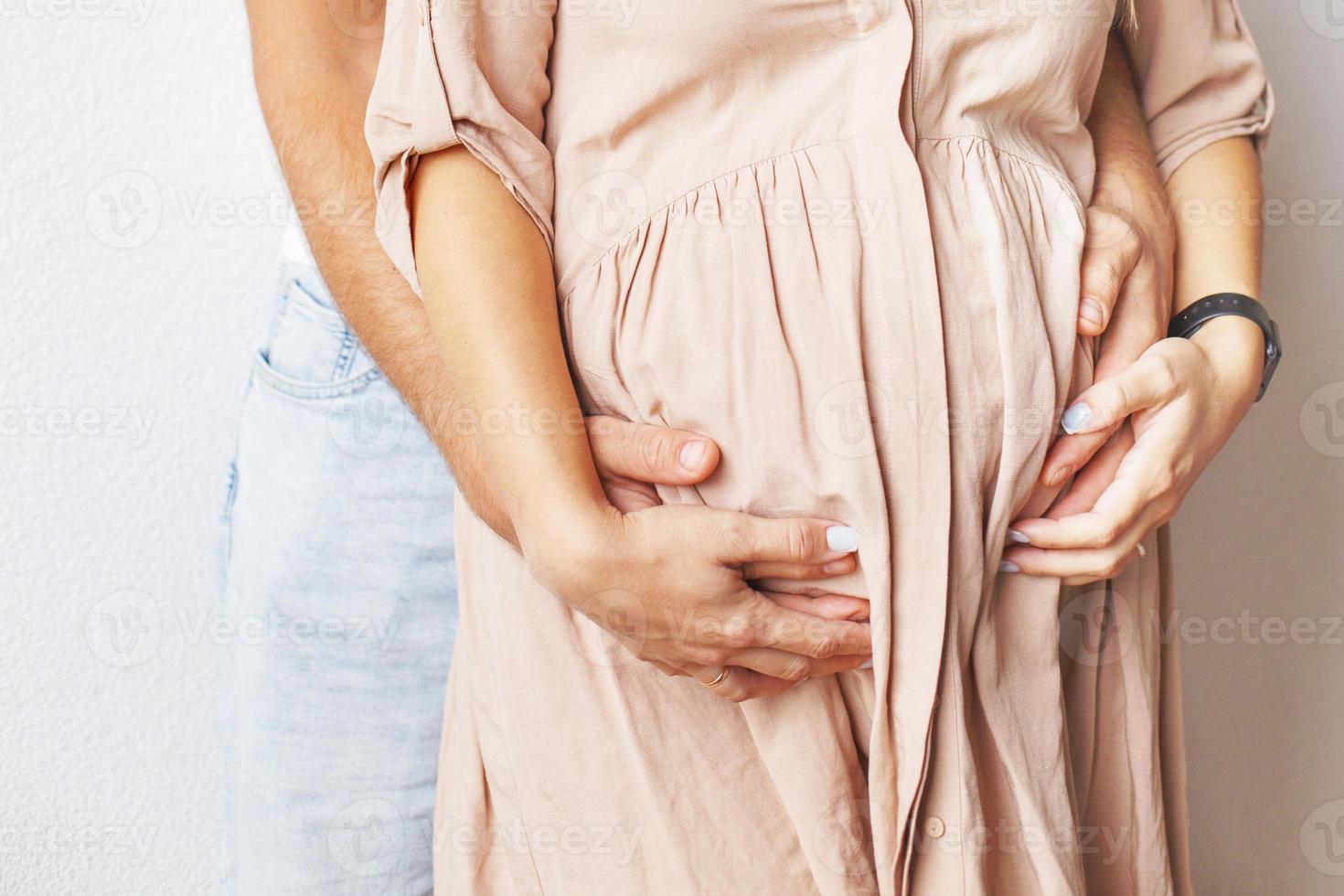 jong zwanger vrouw en man knuffelen haar buik dichtbij foto