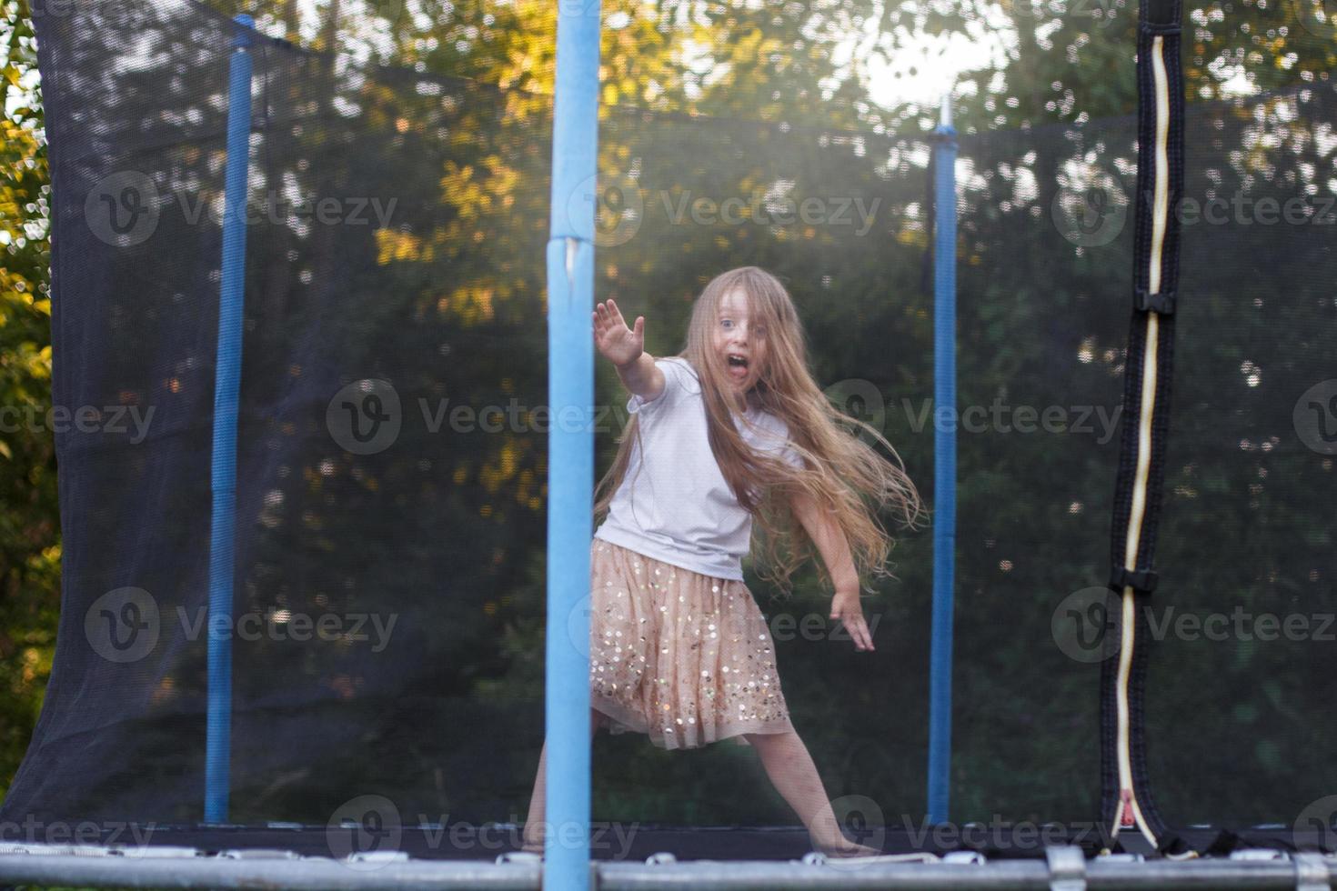 weinig kind meisje jumping Aan de trampoline in de terug werf foto