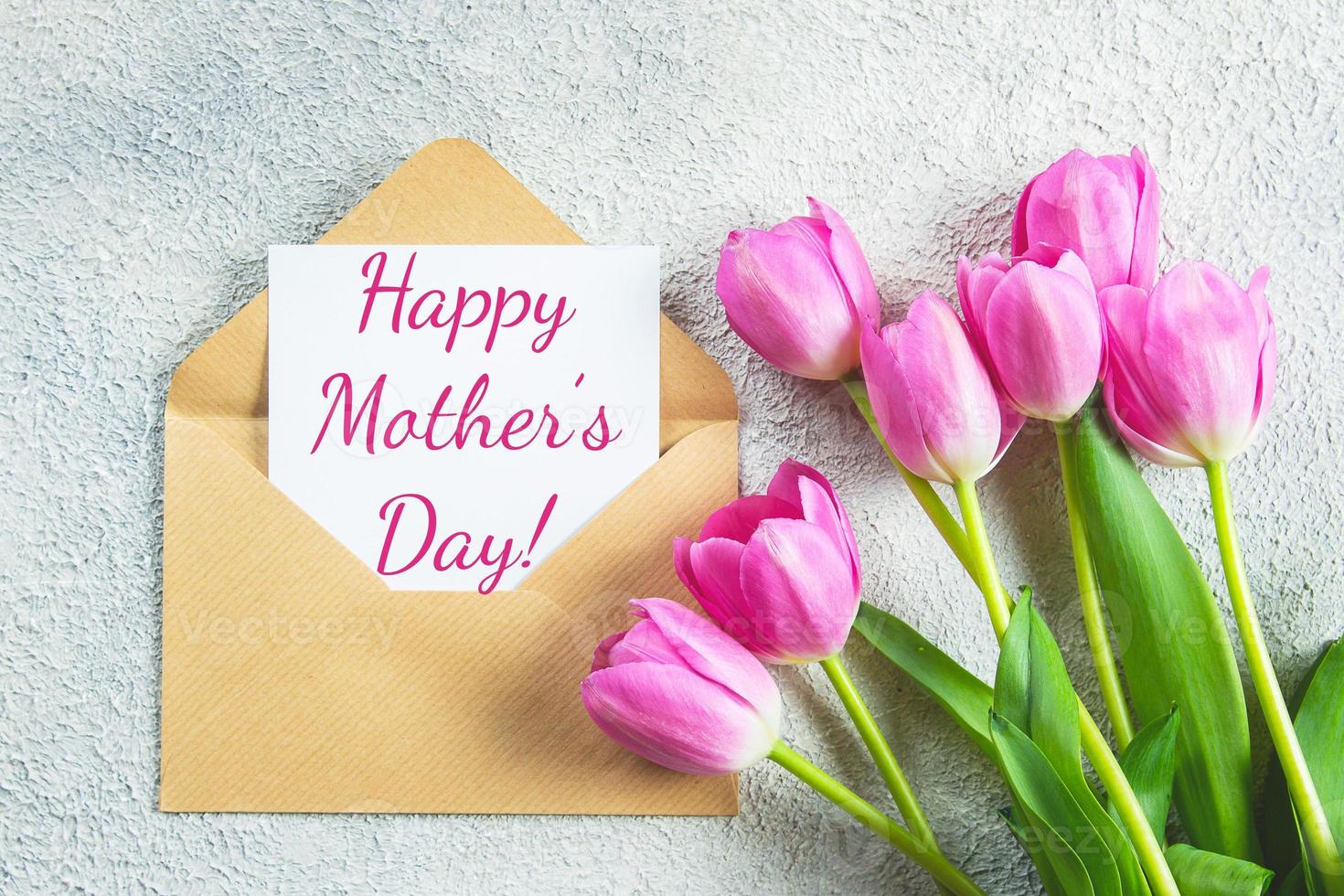 moeder dag vakantie concept. roze tulpen bloemen en kaart Aan beton achtergrond. groet kaart voor vrouwen of moeders dag. vlak leggen, top visie. foto