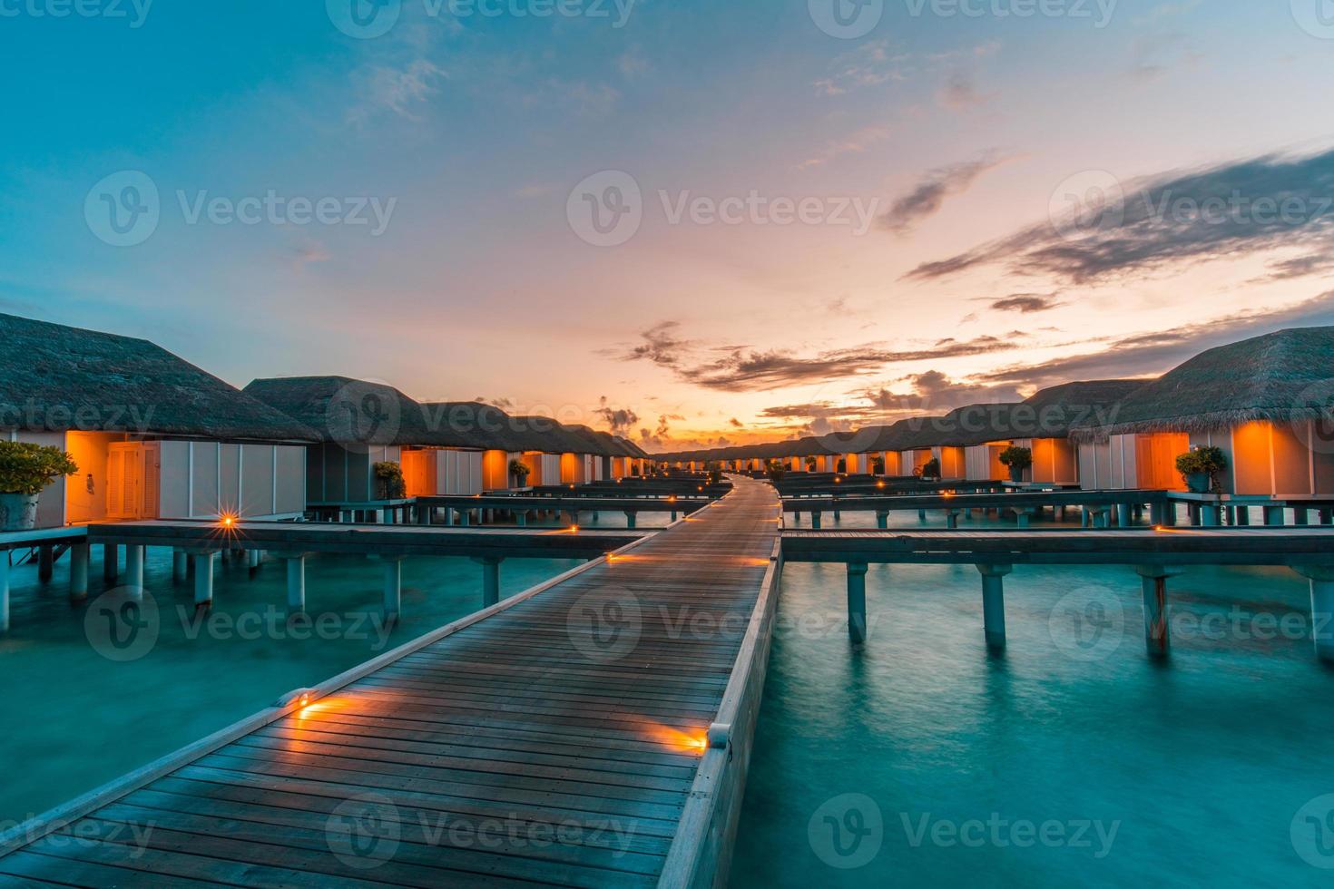 mooi lucht en zee water, luxe tropisch toevlucht, water villa's met lichten onder zonsondergang. zomer eiland achtergrond, luxueus vakantie spandoek. rustig, ontspannende stemming, inspirerend natuur landschap foto