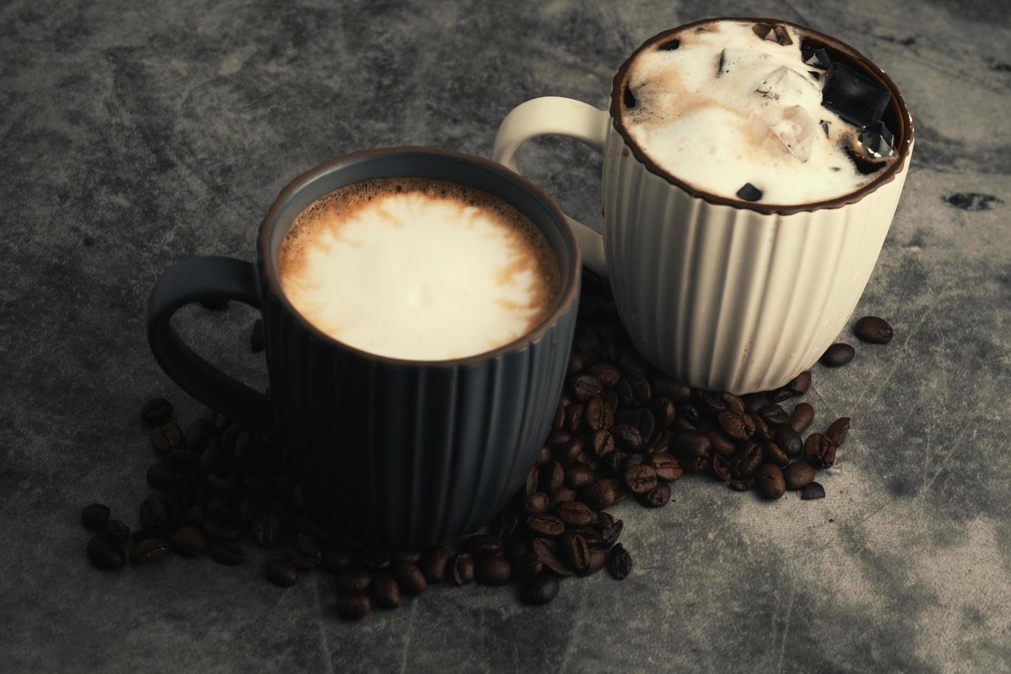 heet latte en bevroren latte met koffie bonen Aan beton achtergrond. foto