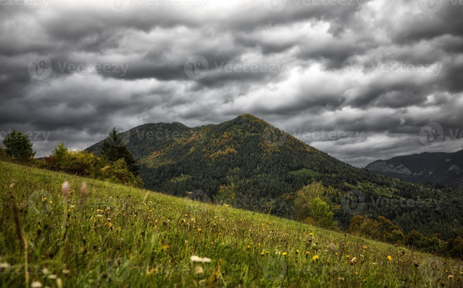 stormachtig wolken Aan de lucht over- herfst land met weide en heuvel Bij achtergrond foto
