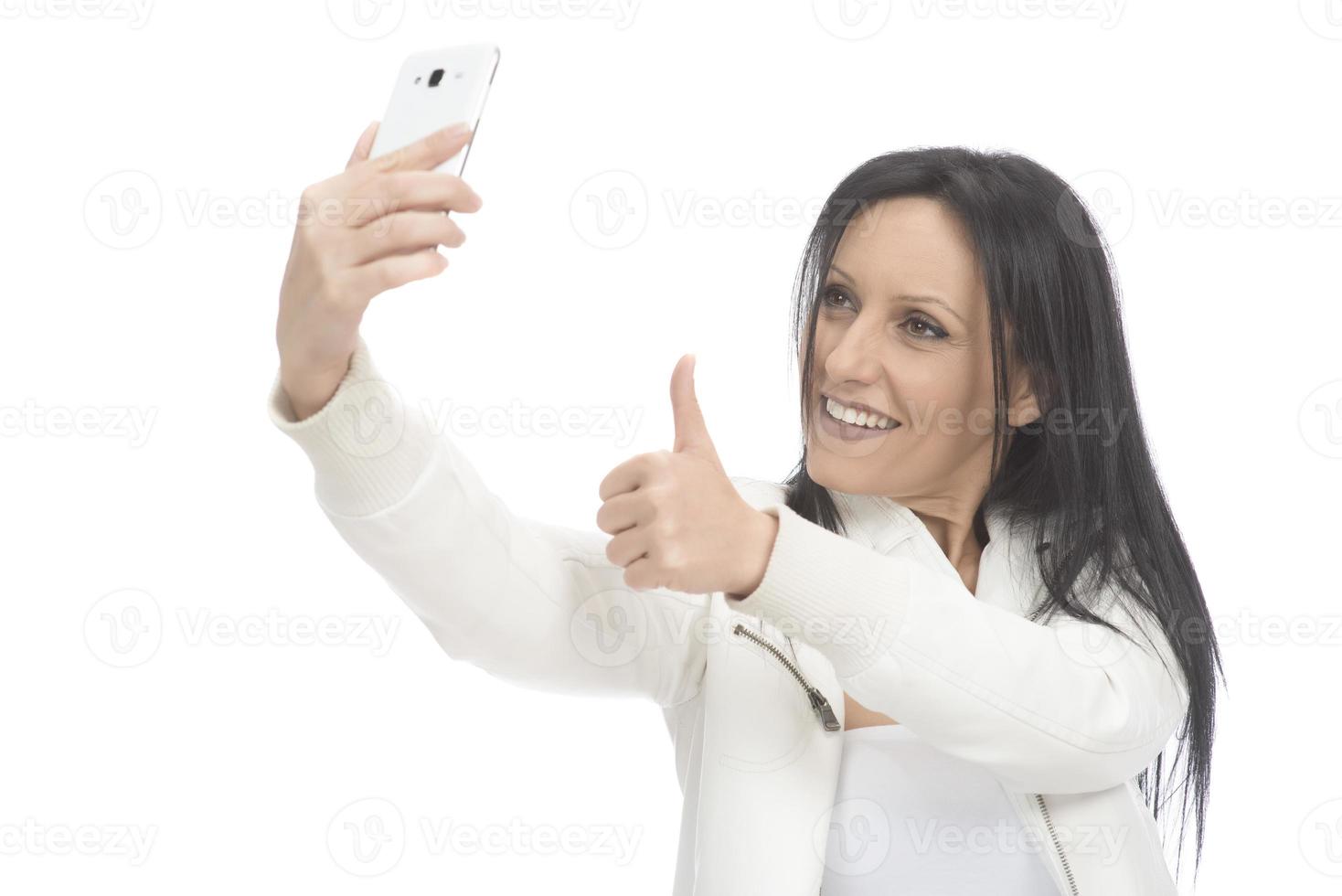 beeld van mooi brunette vrouw lachend terwijl nemen selfie foto Aan mobiele telefoon