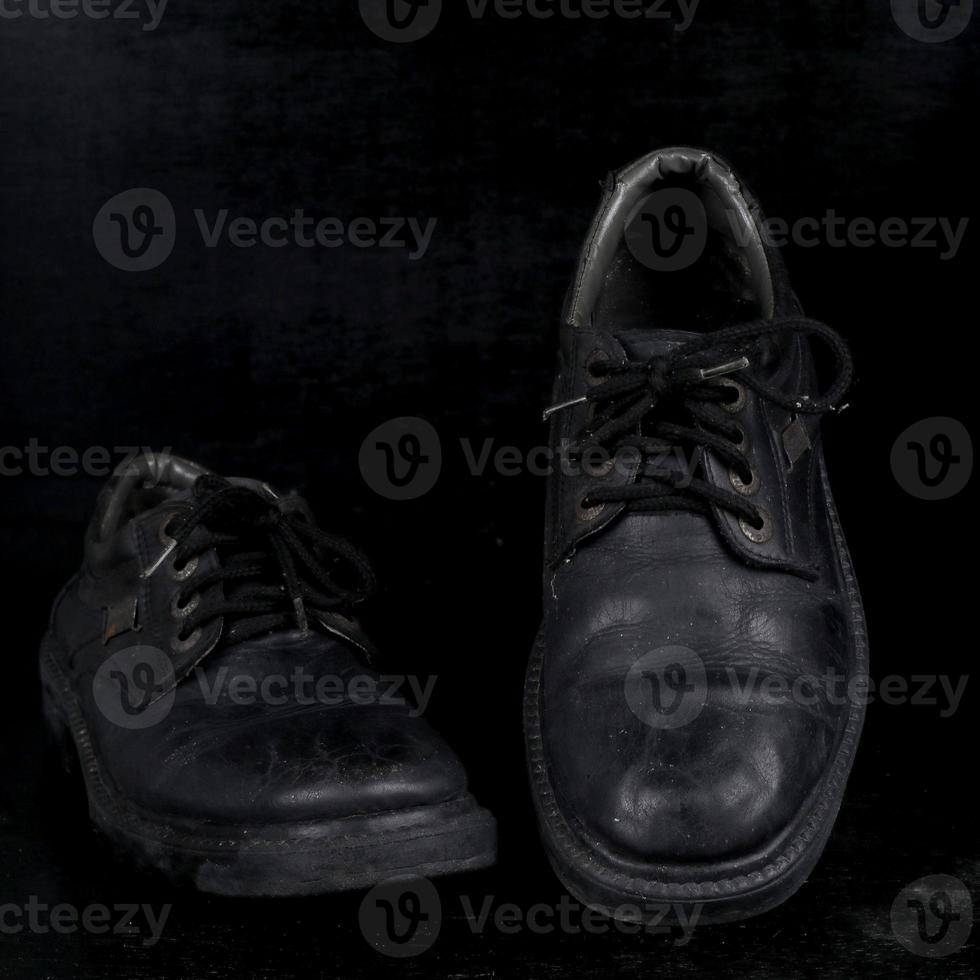 paar- van zwart mannetje klassiek schoenen Aan zwart achtergrond. stoffig schoenen foto