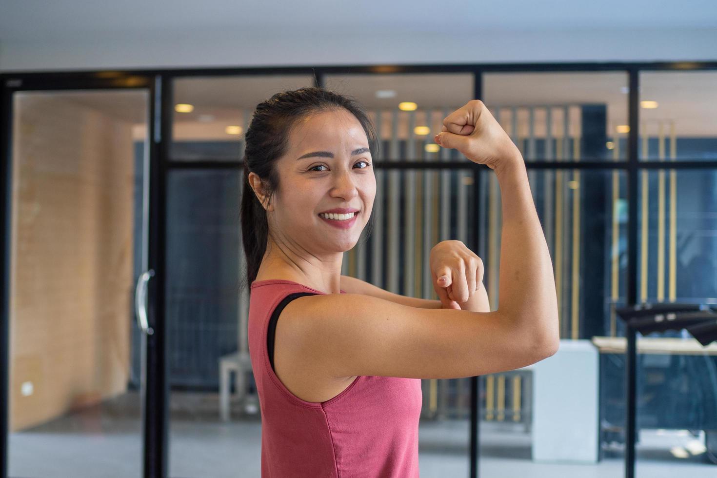 de meisje in de Sportschool strekt zich uit de spieren, shows kracht, mooi zo Gezondheid en glimlacht in de Sportschool. oefening gezond concepten foto