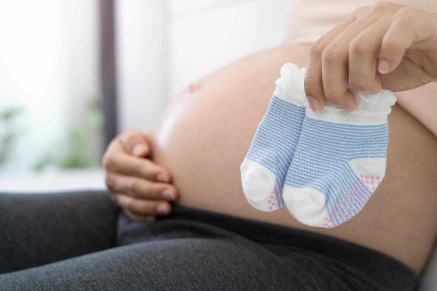 een 8 maand zwanger vrouw is gelukkig naar bereiden sokken voor baby. mooi zo moeder of mam foto