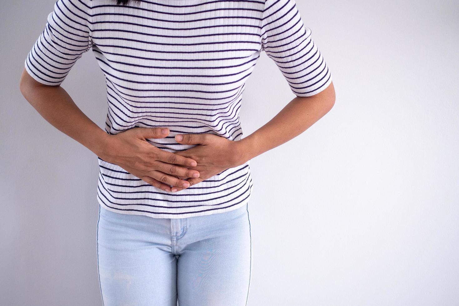 Dames staand en aanraken de buik lijden van menstruatie- krampen en pijn in de lager buik of van streek maag van voedsel vergiftiging. foto