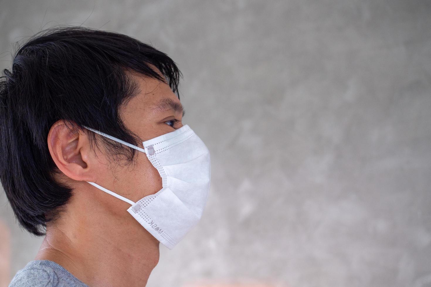 een Mens is vervelend een masker naar voorkomen de covid-19 virus dat is verspreiden in de omgeving van de wereld of voorkomen pm2.5. iedereen moet toetreden handen naar hou op de dodelijk infectie. foto