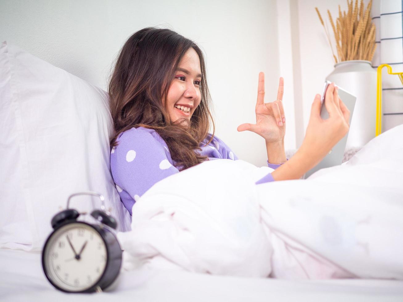 een vrouw is verslaafd naar een smartphone naar video babbelen met haar vriendje tot laat Bij bedtijd. foto