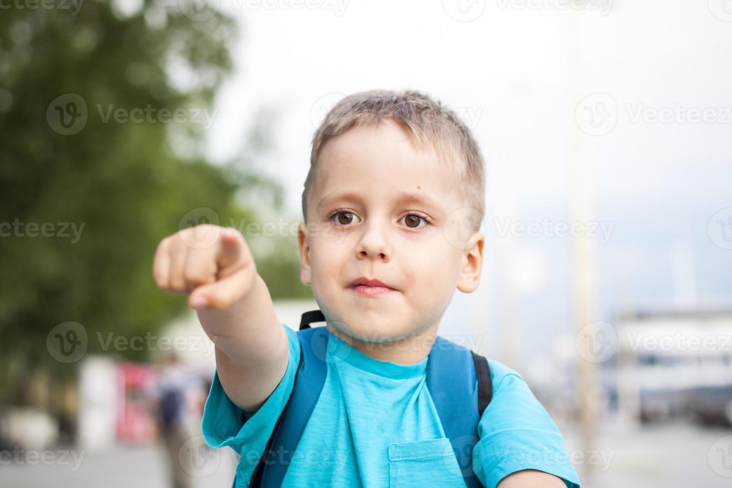 een jongen in een blauw t-shirt met een rugzak Aan zijn rug. reis. de gezicht drukt uit natuurlijk blij emoties. niet geënsceneerd foto's van natuur foto