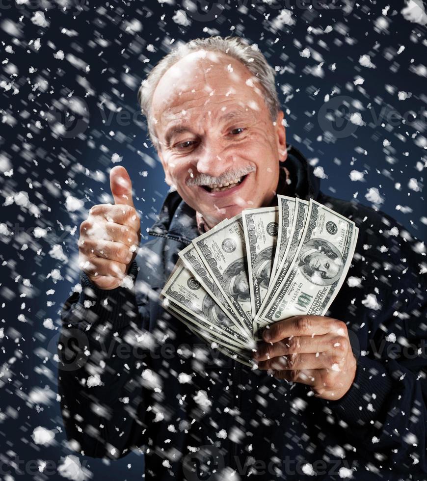 Mens met een bundel van dollars in sneeuwval foto