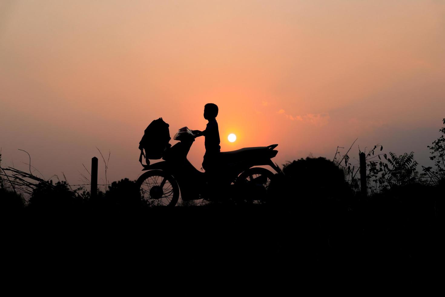 silhouet van kleine jongen op een motorfiets foto