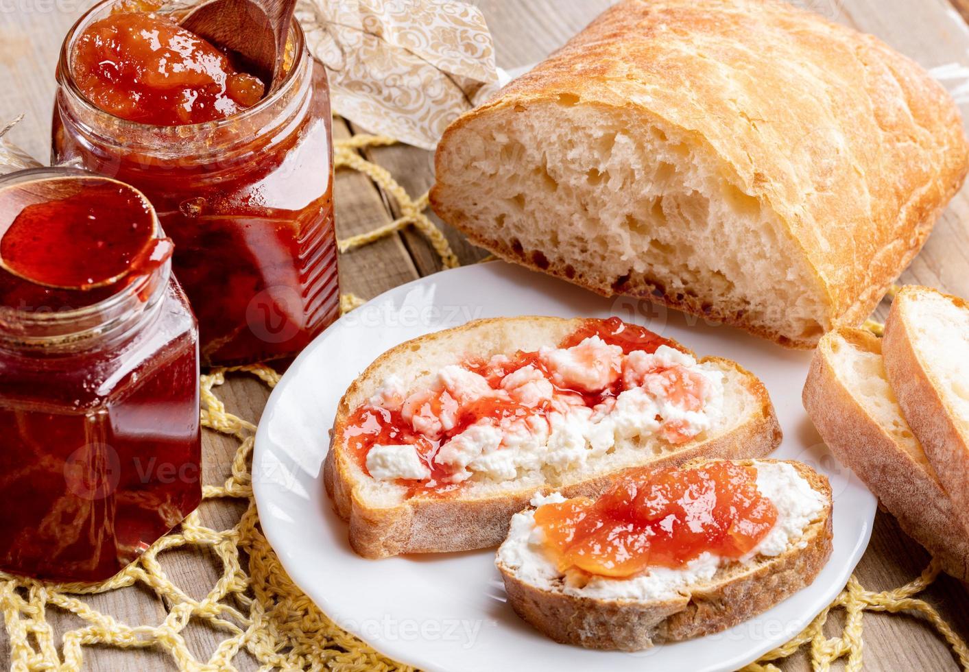 toast en glas potten met aardbei en appel jam Aan geel gebreid servet Aan houten tafel. foto