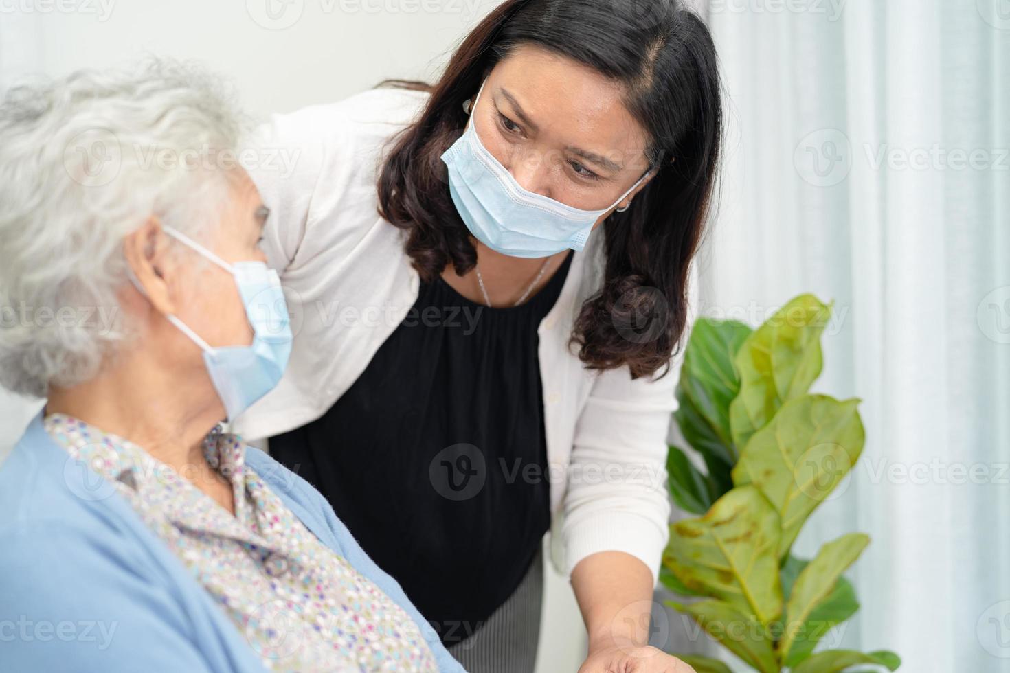 verzorger helpt aziatische senior of oudere oude dame vrouw zittend op een rolstoel en het dragen van een gezichtsmasker ter bescherming van de veiligheidsinfectie covid19 coronavirus. foto