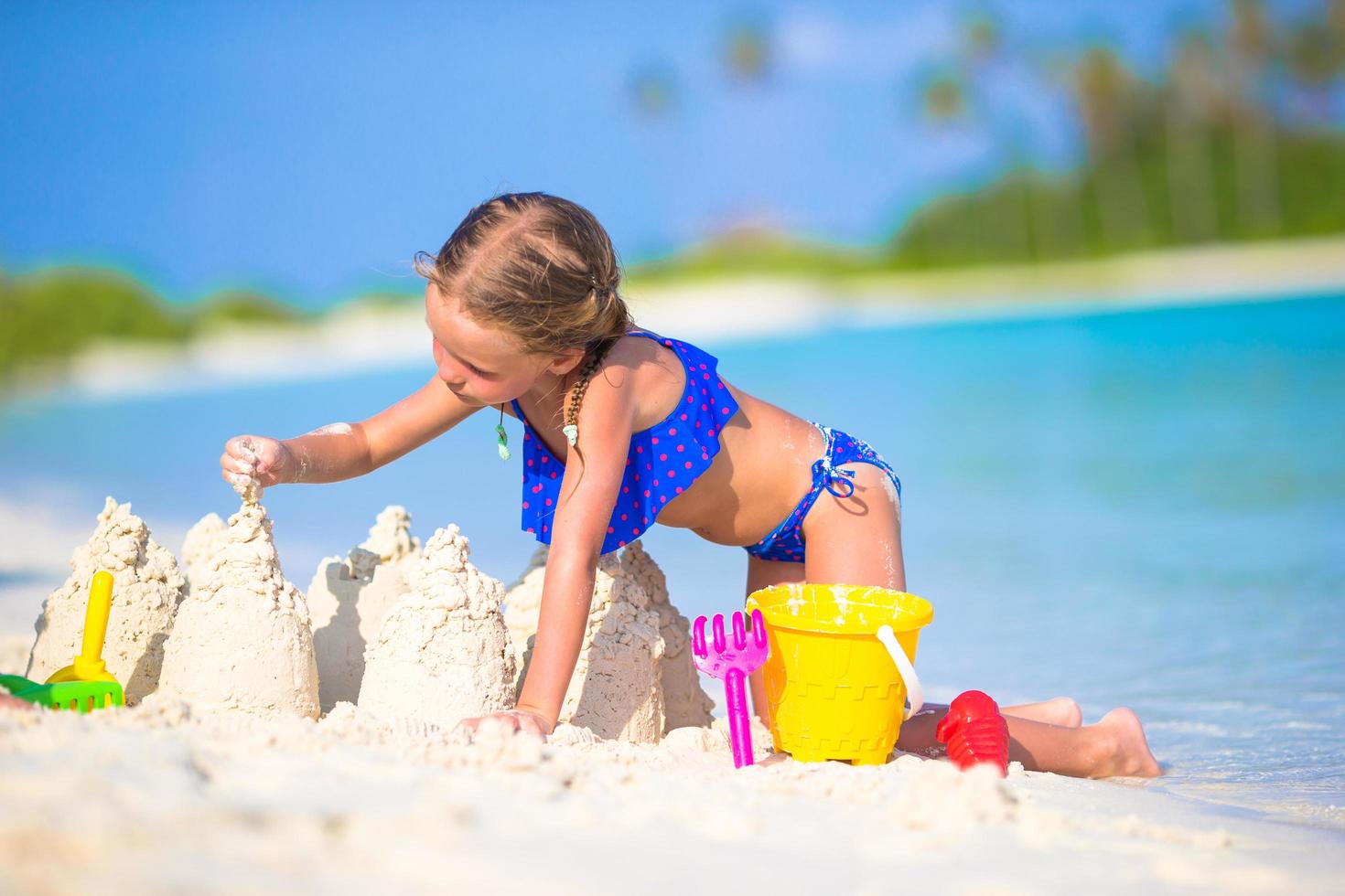 meisje bouwt een zandkasteel in wit zand foto