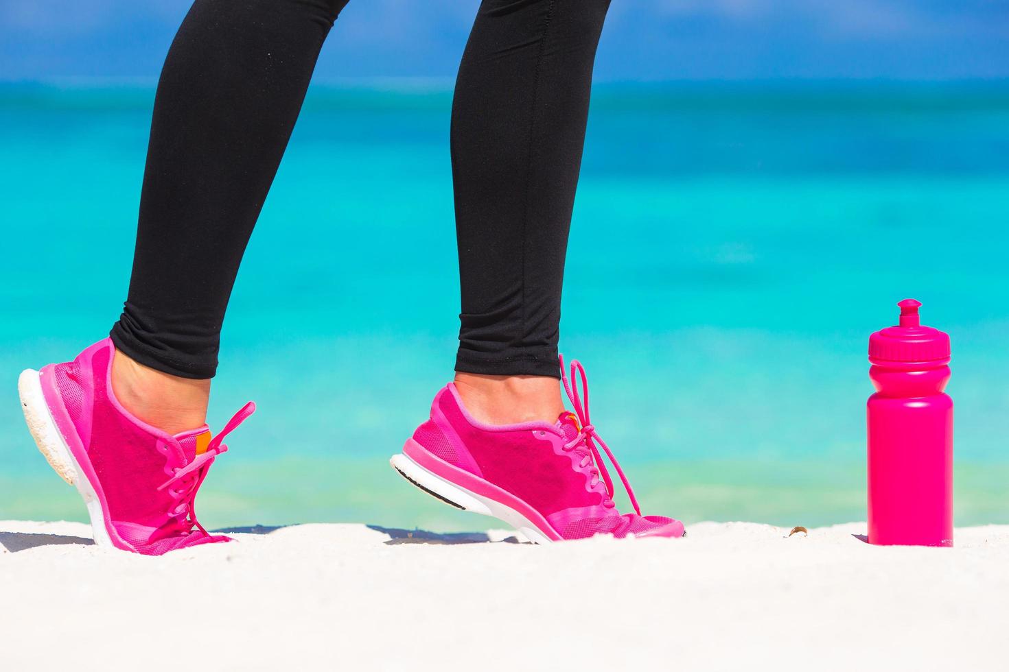 vrouw in roze schoenen op een strand foto