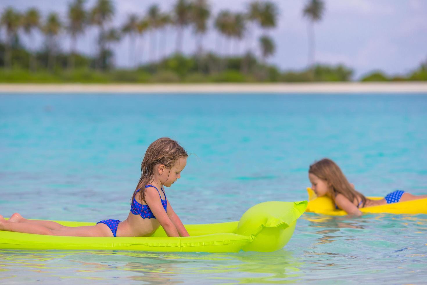 twee meisjes op drijvers in het water foto