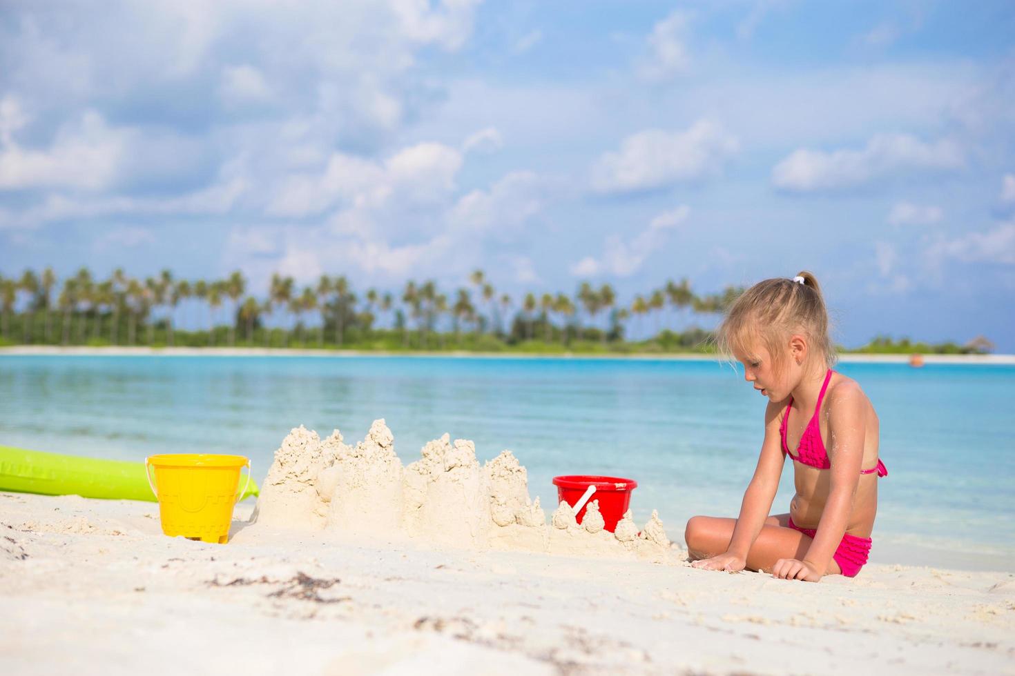 meisje bouwt een zandkasteel op een strand foto