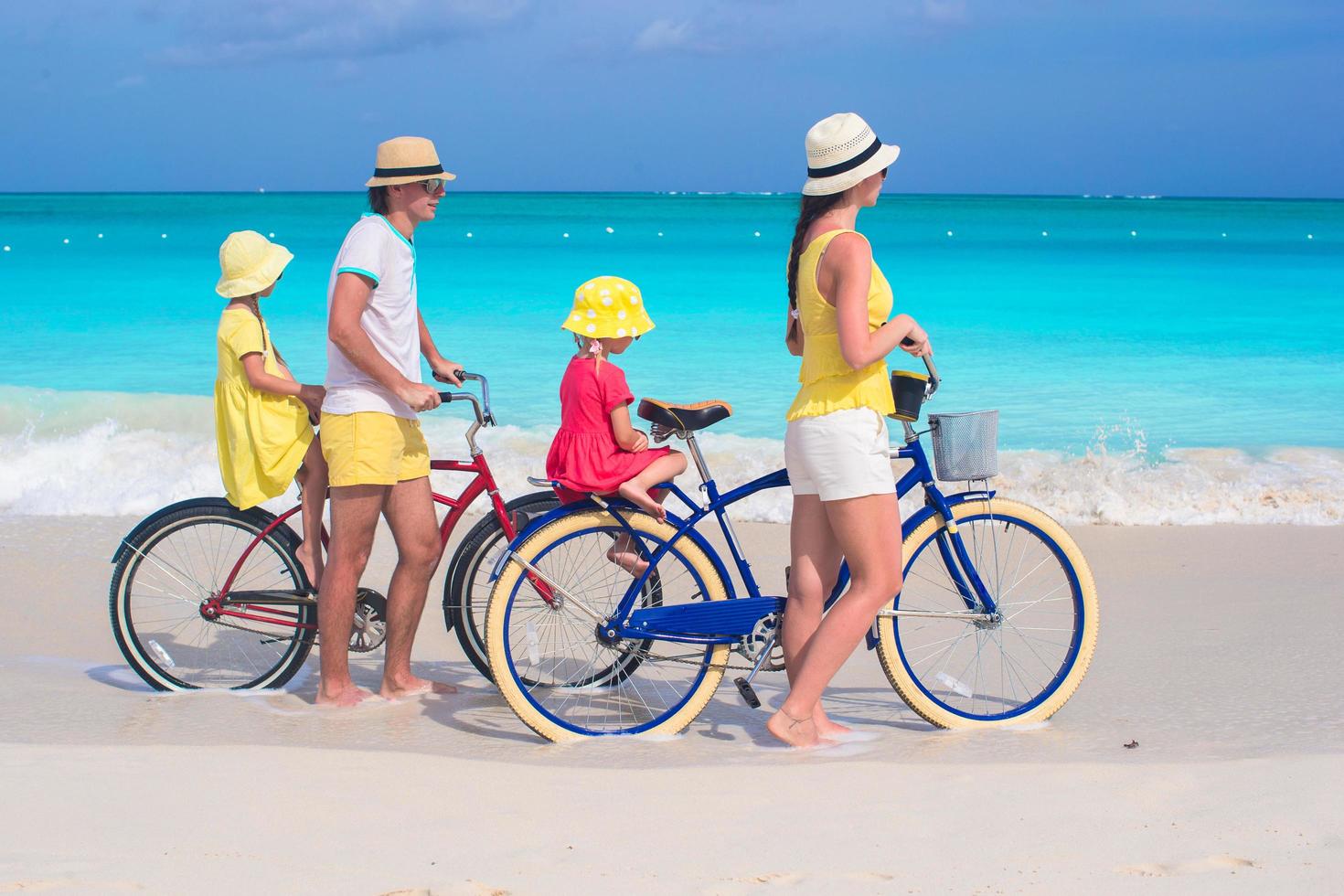 gezin van vier fietsen op een tropisch strand foto