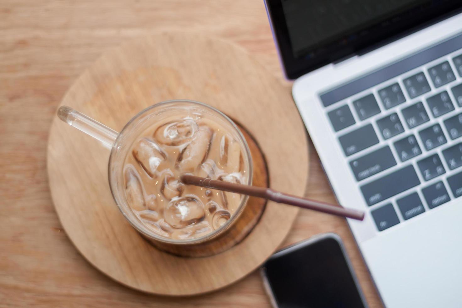 ijskoffie naast een laptop en telefoon foto