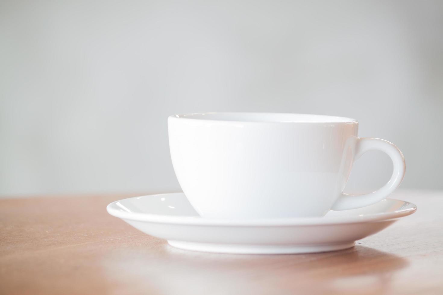 witte koffiekopje op een houten tafel en een grijze achtergrond foto