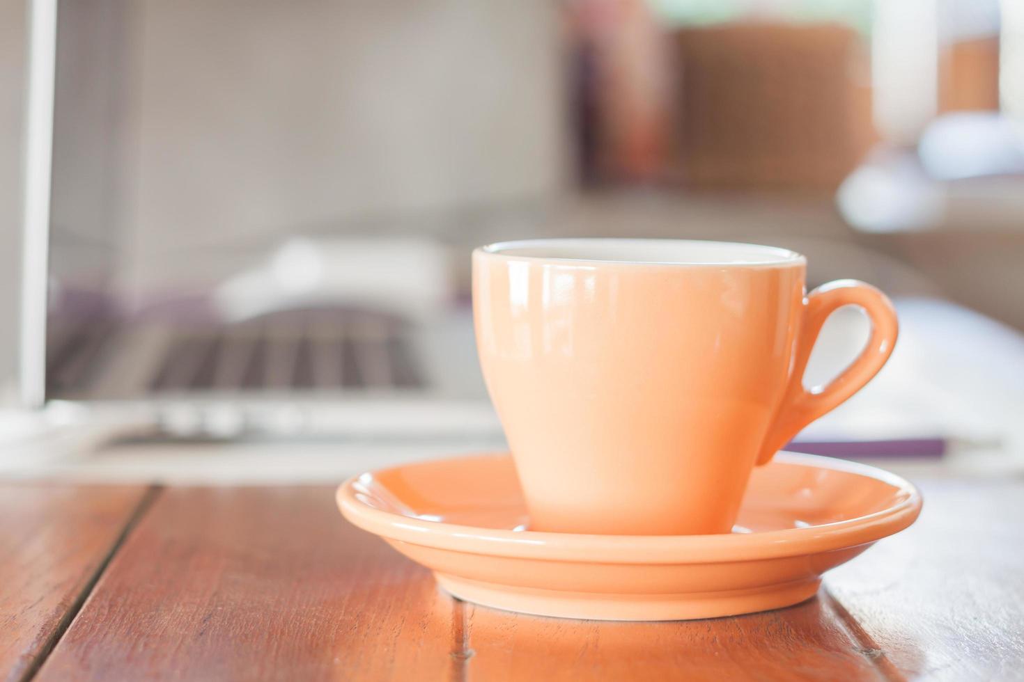 oranje koffiekopje op een werkplek foto