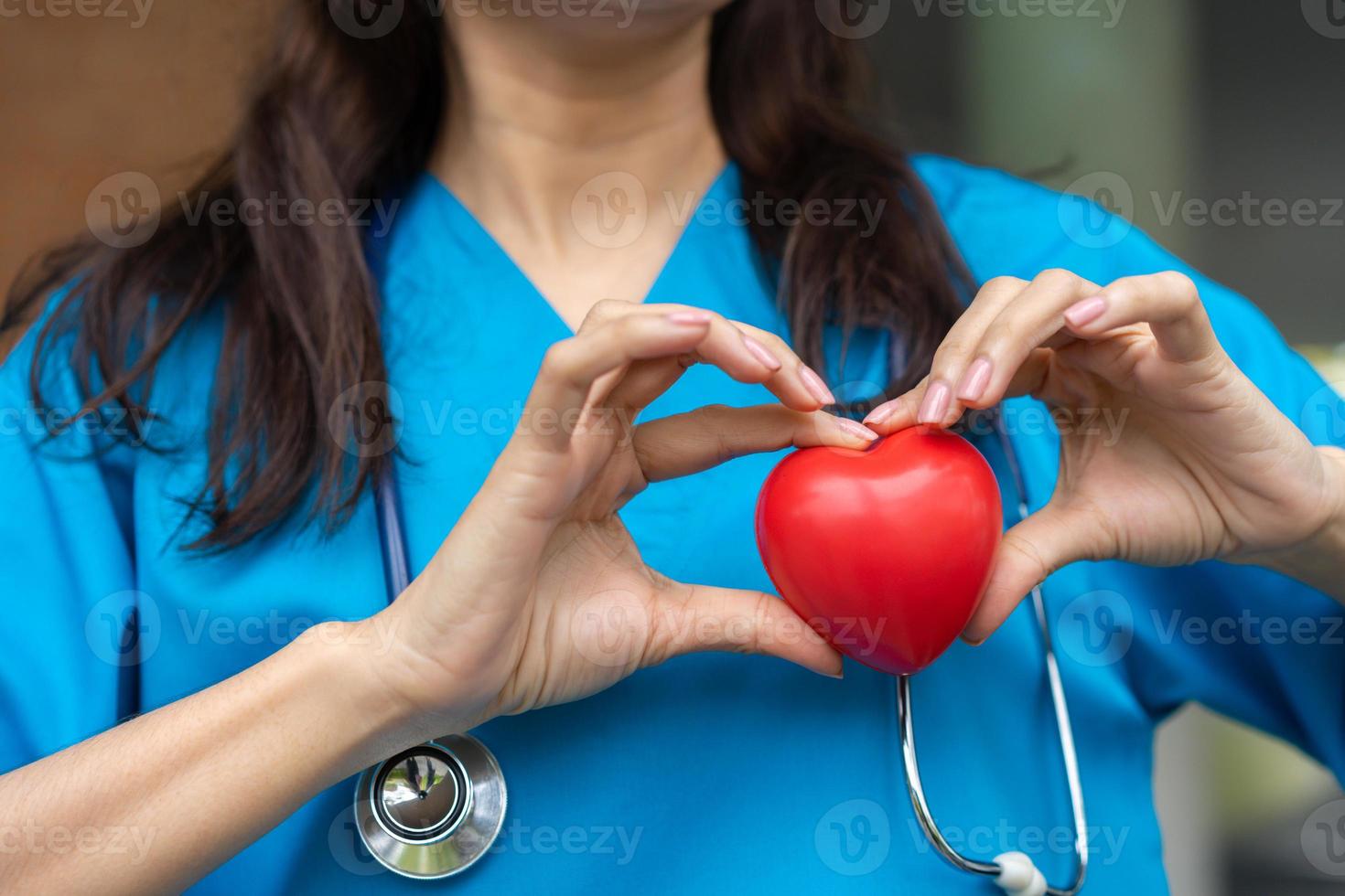 vrouw cardiovasculair ziekte dokter of cardioloog met stethoscoop Holding rood hart, medisch Gezondheid zorg en dokter personeel onderhoud concept. foto