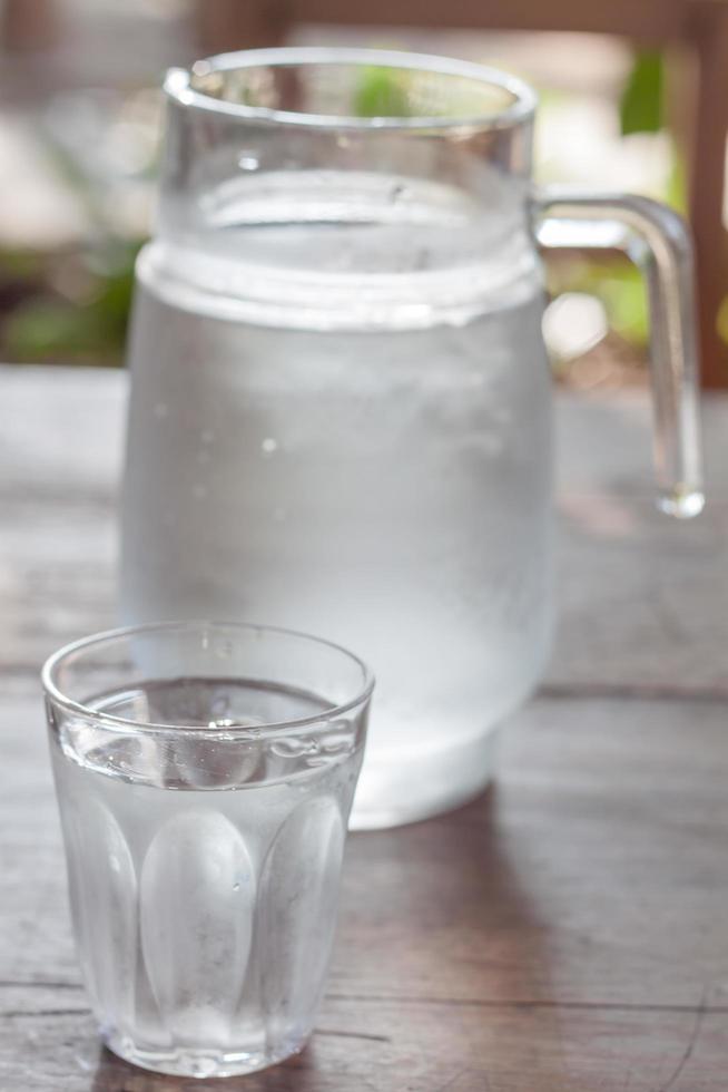 glazen kruik koud water met beker foto