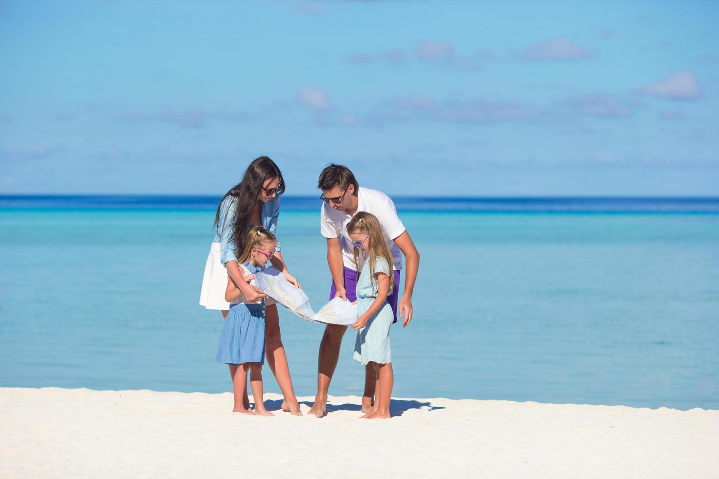 familie kijken naar een kaart op een strand foto