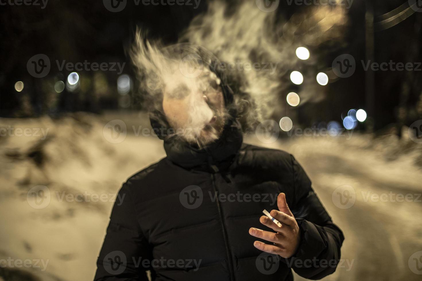 vent rookt sigaret. Mens rookt buiten. jong Mens in zwart jasje. slecht gewoonte. foto