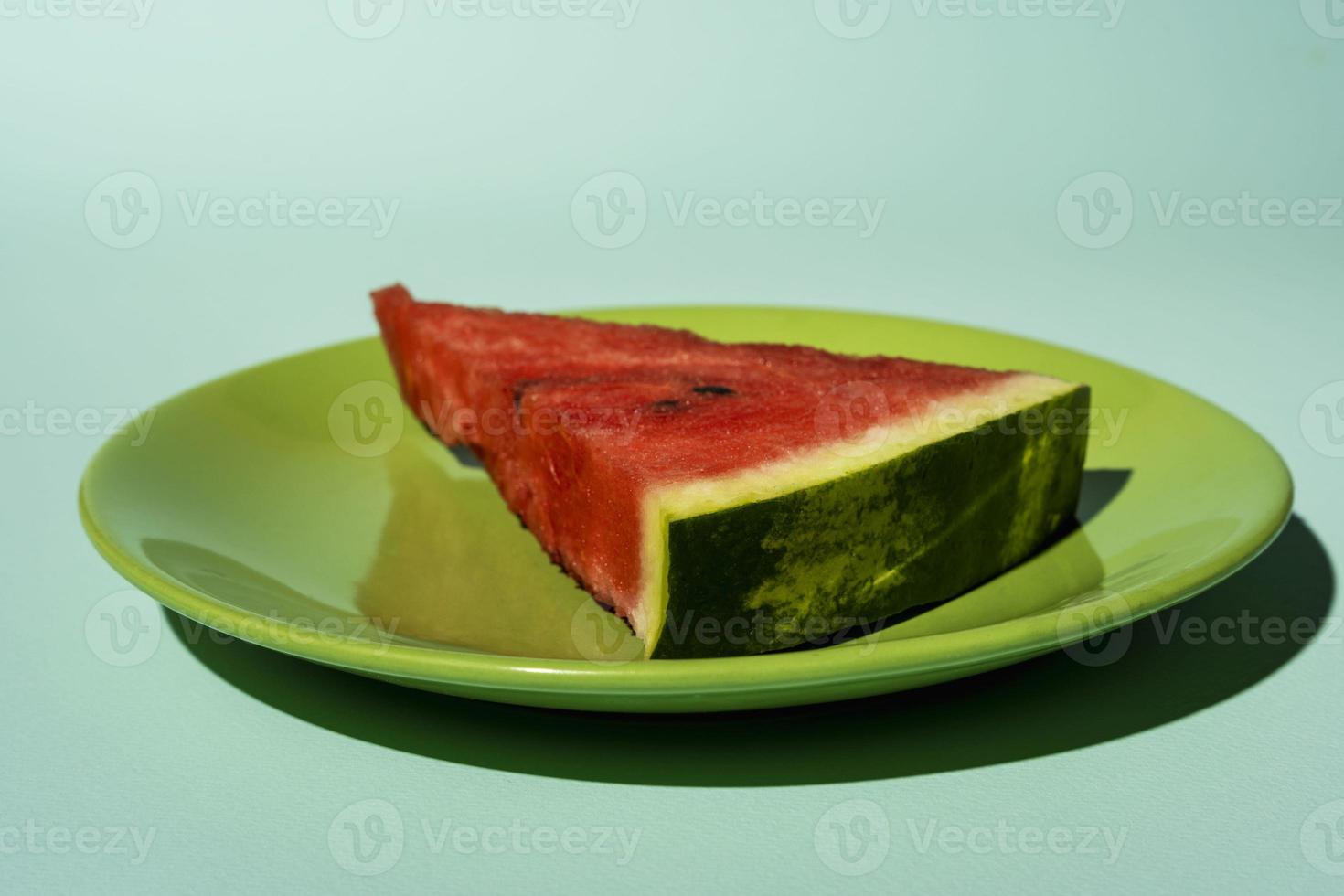 watermeloen plak Aan een bord Aan een turkoois achtergrond, kant visie foto