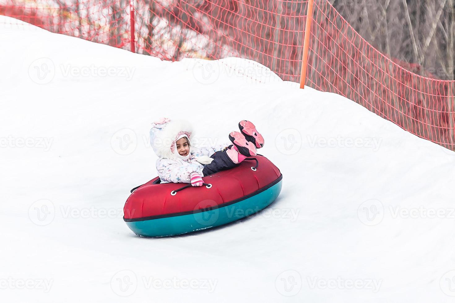 weinig meisje met sneeuwbuis klaar voor rodelen naar beneden een heuvel foto