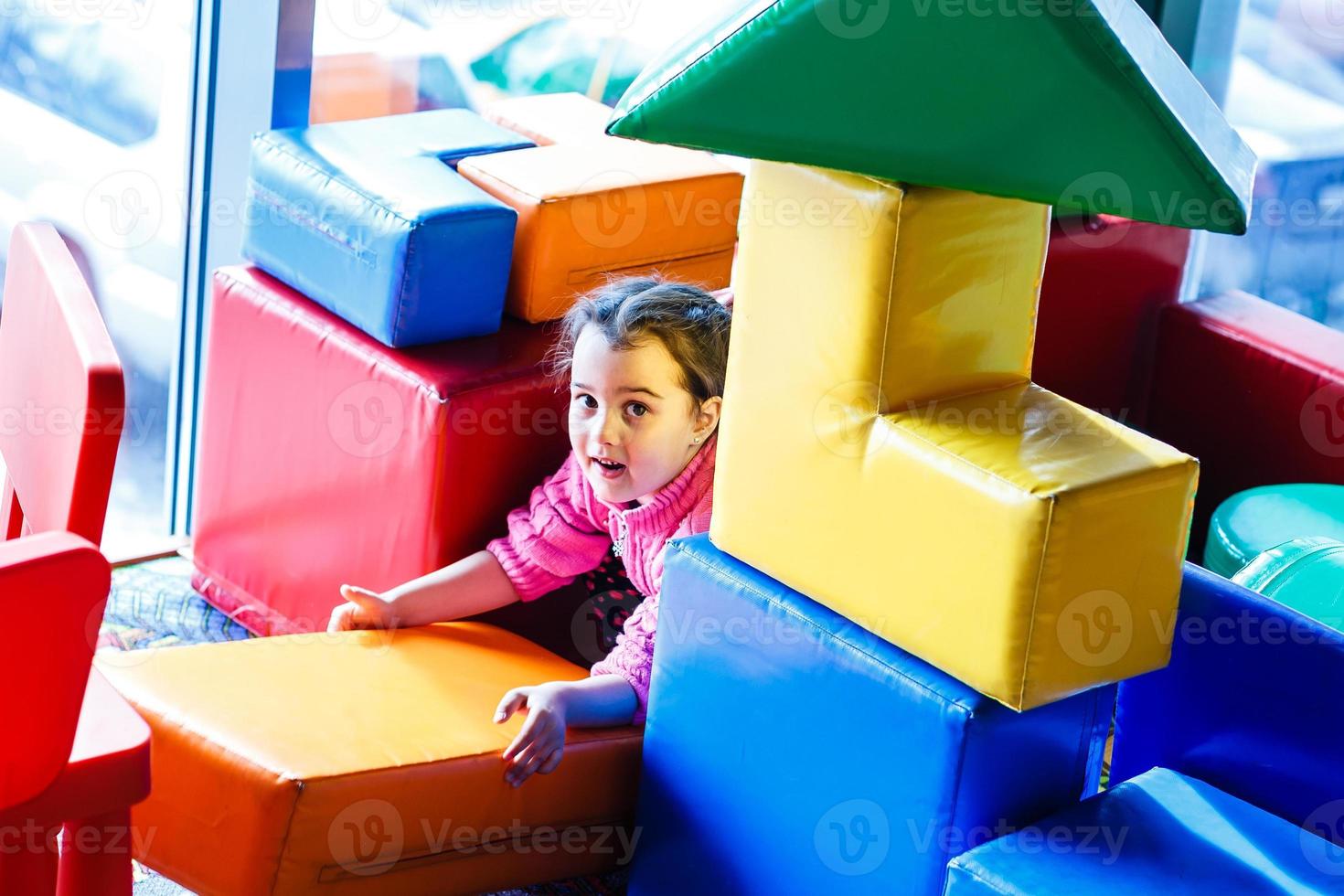 meisje spelen Aan de gedekt speelplaats Aan de trampoline met zacht schuim veelkleurig kubussen. de concept van jeugd. foto